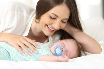 Wall Mural - Mother watching her baby sleeping on a bed