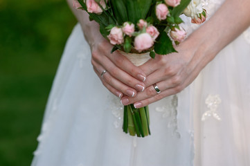 Wall Mural - Hands of the bride with a gold ring hold a wedding bouquet