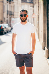 Wall Mural - Hipster handsome male model with beard  wearing white blank  t-shirt with space for your logo or design in casual urban style