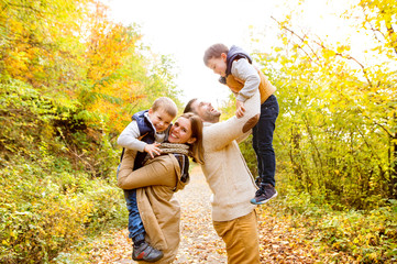 Beautiful young family on a walk in autumn forest.