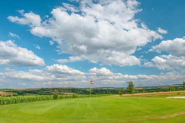 Wall Mural - Golf course landscape Golf field green grass red flag blue sky