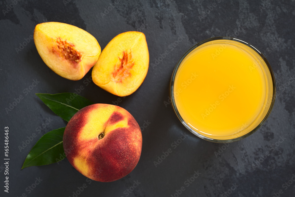 Peach juice or nectar in glass with fresh ripe peach fruit on the side, photographed overhead with natural light (Selective Focus on the juice and the top of whole fruit) - obrazy, fototapety, plakaty 