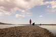 © carlosobriganti - Man and his dog walking on the sandy path across the lake on a beautiful summer sunset