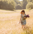 Woman walks with bouquet of lavander across the field