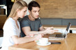 © LIGHTFIELD STUDIOS - young couple working on laptop together while sitting at table in cafe