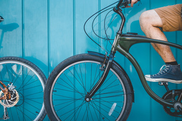 Wall Mural - Unrecognizable Young Cyclist Sitting With A Bicycle Along A Blue Wall Background Daily Lifestyle Urban Resting Concept