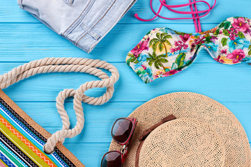 Wall Mural - Beach clothing close up. Woven hat, colorful bra, shorts, sunglasses, handbag.