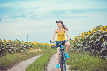 Wall Mural - Young bicyclist riding in sunflower field