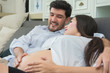pregnant woman and husband are happy couple expecting a baby on sofa