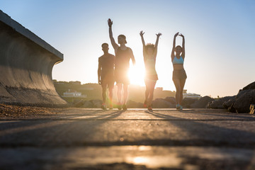 Wall Mural - Group of runners working out on a road by the sea