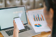 © jannoon028 - Business woman hand with Financial charts and mobile phone over laptop on the table .
