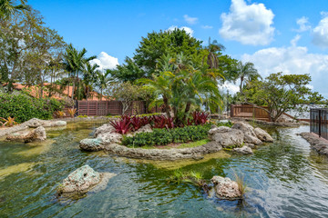 View looking at pond with tropical-inspired landscaping. 