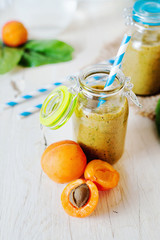 Wall Mural - Healthy food, summer drinks, fruit and vegetable smoothie with banana, apricot and spinach in glass bottles on a light background, detox