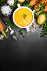 Wall Mural - Carrot cream-soup on black table.