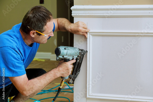 Cuadros en Lienzo Carpenter using a brad nail gun to complete framing trim