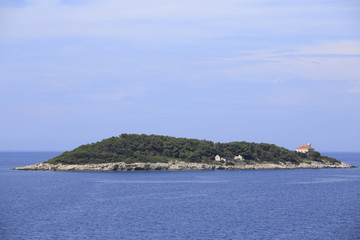 Island with small house on rocks, Photo of small island with boats and blue sea in the background