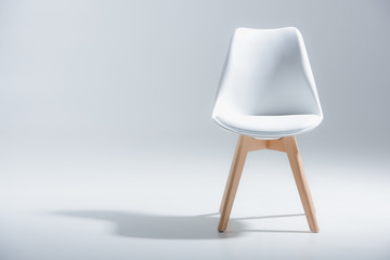 studio shot of stylish chair with white top and light wooden legs standing on white