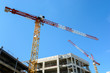 © olrat - Two tower cranes with a concrete building under construction