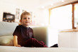 © NDABCREATIVITY - Happy boy sitting on living room couch