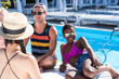 © LIGHTFIELD STUDIOS - Group of young multiethnic friends rest at poolside during vacation at resort