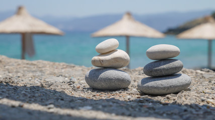 Two pebble towers with sun umbrellas on a sea shore