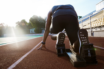 Back view of a young man in starting position for running