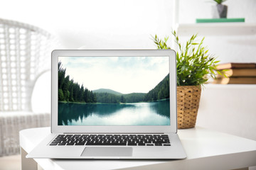 Workplace with laptop and wallpaper of landscape on screen