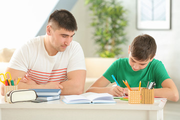 Canvas Print - Father and son doing homework together indoors