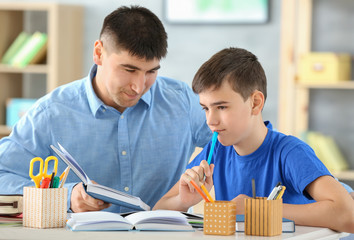 Canvas Print - Father and son doing homework together indoors