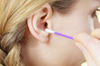 © Voyagerix - Woman cleaning ear with cotton swabs closeup