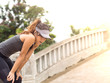 Female runner athlete resting and catching the breath after marathon training in the park at sunset, Standing bent over 