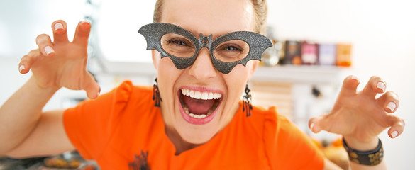 smiling young woman in Halloween decorated kitchen frightening