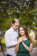 © Olga Mishyna - Couple in love: young girl in a long green dress and balding man in the garden. Spring or summer love story