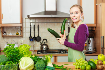 Woman housewife in kitchen with green vegetables