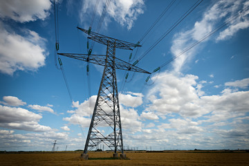 high voltage pylons on blue cloudy sky background