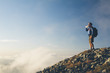 © Paul Edmondson/Stocksy - Man standing on mountain summit, drinking from bottle of water at dusk