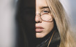 © Alexey Kuzma/Stocksy - closeup of blond woman with round glasses