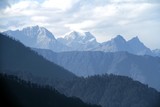 Fototapeta Góry - Morning mountain landscape with layer of mountain peaks covered with coniferous deciduous forests. View from Dochula Pass on the road from Thimphu to Punaka, Bhutan