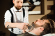 © nagaets - Master cuts hair and beard of men in the barbershop