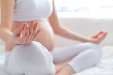 Beautiful pregnant woman exercising while sitting in lotus position