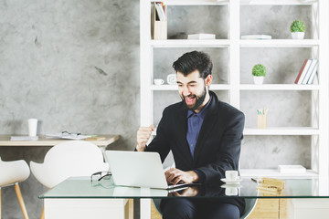 Canvas Print - Happy businessman using laptop at workplace