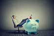 © pathdoc - businesswoman with big piggy bank relaxing sitting on chair