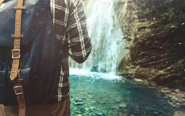 Wall Mural - Unrecognizable Traveler Man With Backpack Reached His And Stands On Waterfall Background Closeup Hiking Journey Travel Trek Concept