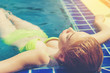 © Panumas - pretty woman in green bikini relaxing in the corner of swimming pool on vacation