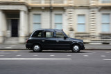 Fototapeta Koty - Panning shot of a black taxi in London.