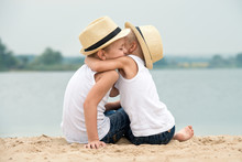  Two Brothers Relaxing On The Beach Of The Lake.The Little Boy Tenderly Embraces His Older Brother.