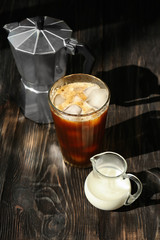 Wall Mural - Glass with cold brew coffee and milk in small jug on wooden table