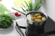 Metal pot with potato on induction cooker in kitchen