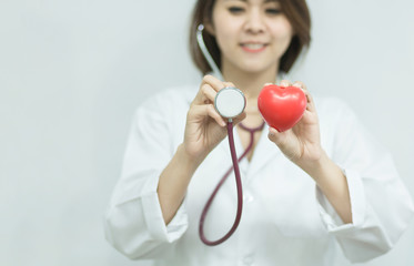 Close-up of female doctor holding red heart, in health checking concept.