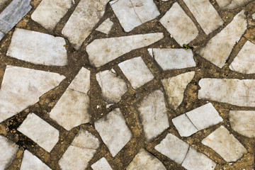 Old weathered stone tiles. Remains antique abandoned terrace. Fragments, pieces, flinders, debris, details, decor. Broken marble texture for design, templates, backgrounds, textures, prints, work.